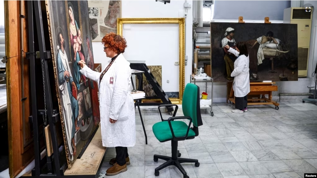 Restorers Alessandra Zarelli and Rossana Giardina work on paintings at the "painting and wood materials restoration laboratory" inside the Vatican Museums, at the Vatican, December 11, 2023. (REUTERS/Guglielmo Mangiapane)