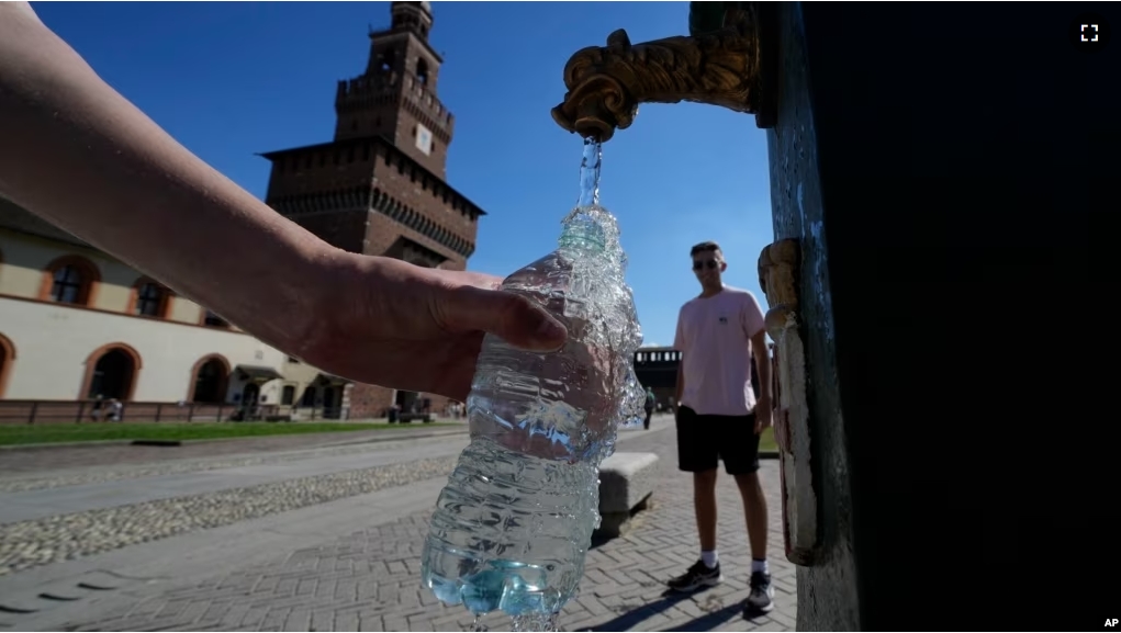 FILE - Tourists fill plastic bottles with water from a public fountain at the Sforzesco Castle, in Milan, Italy, June 25, 2022. (AP Photo/Luca Bruno, File)