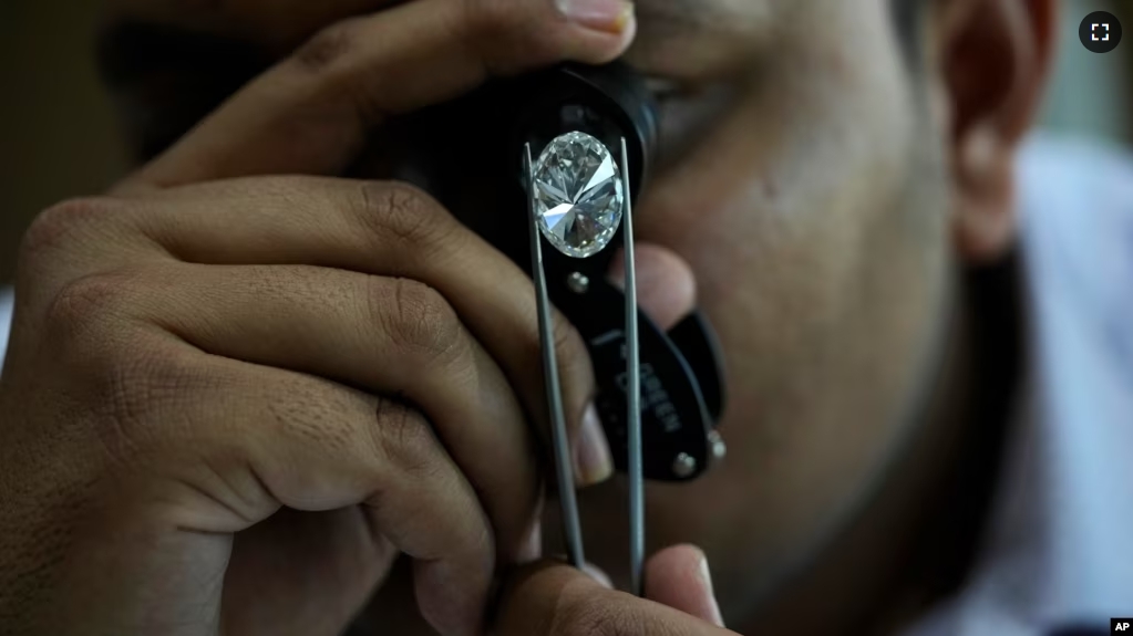 A man looks at a polished lab-grown diamond at Greenlab Diamonds, in Surat, India, Monday, Feb. 5, 2024. Diamonds, whether lab grown or natural, are chemically identical and entirely made out of carbon. (AP Photo/Ajit Solanki)