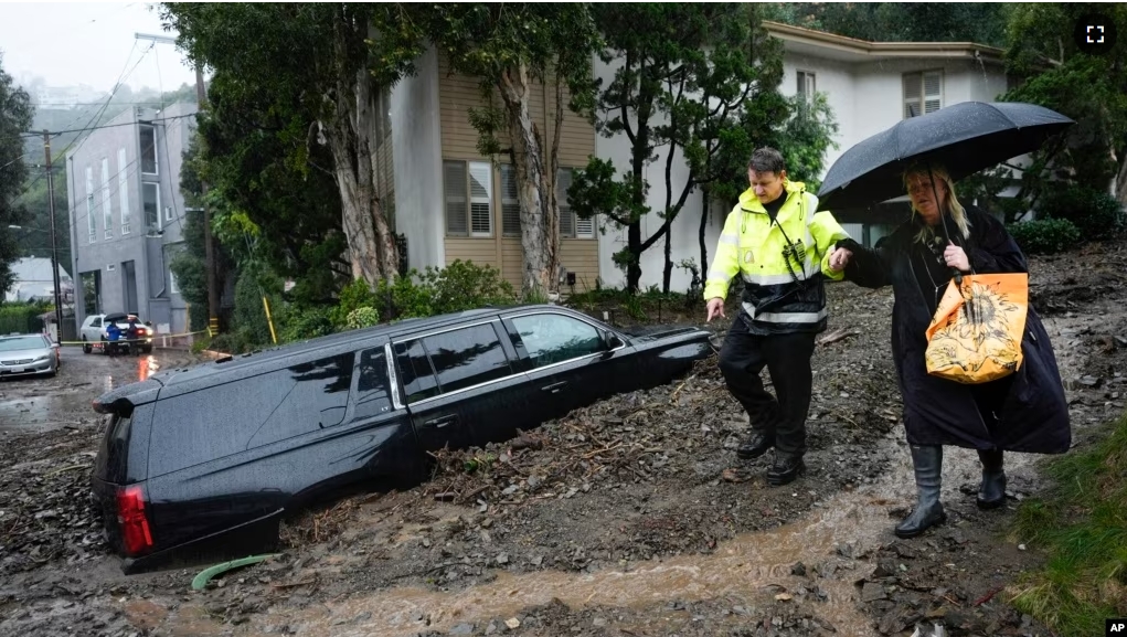 An emergency worker helps a resident escape from danger after a mudslide, February 5, 2024, in the Beverly Crest area of Los Angeles, California. (AP Photo/Marcio Jose Sanchez)