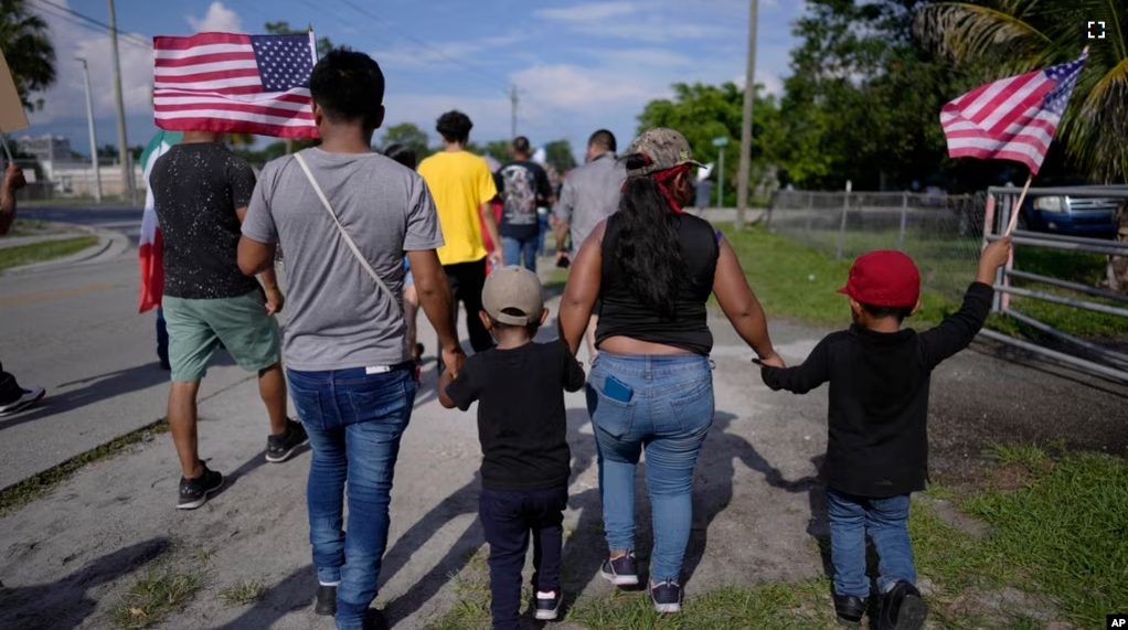 FILE - Carrying American flags, immigrants march during a peaceful protest against a Florida legislation restricting undocumented immigrants, Thursday, June 1, 2023, in Immokalee, Florida. (AP Photo/Rebecca Blackwell)