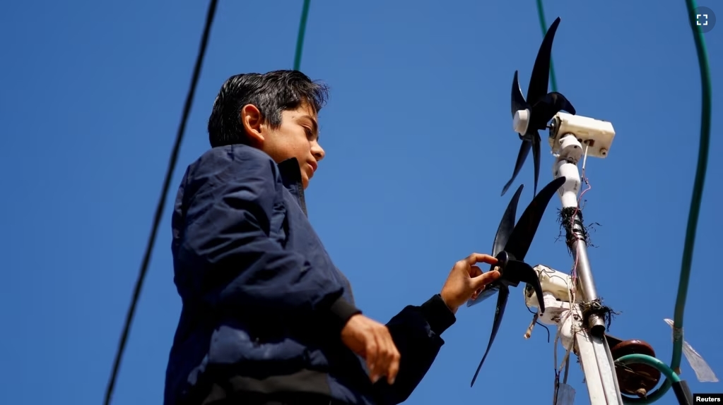 Displaced Palestinian teenager Hussam Al-Attar works on wind turbines, that he uses to light up his shelter during power cut, at a tent camp in Rafah, in the southern Gaza Strip, February 6, 2024. (REUTERS/Ibraheem Abu Mustafa)