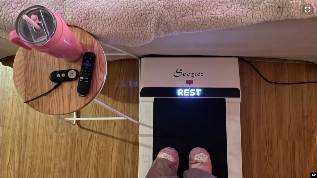 FILE - Hope Zuckerbrow, founder of the cozy cardio wellness movement, shows her workout set-up, including a walking pad, smoothie and remote control for watching television. (Hope Zuckerbrow via AP)