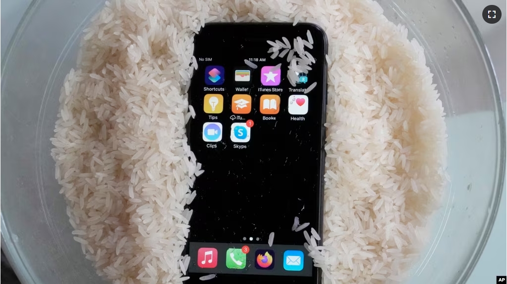 A view of a wet smartphone placed in a bowl of rice to dry, in London, Wednesday, Feb. 28, 2024. (AP Photo/Frank Augstein)