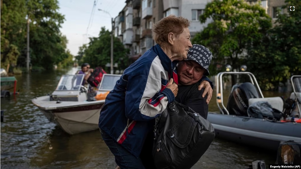 FILE - A volunteer carries a woman as she is evacuated from a flooded Kardashynka village of the bank Dnipro river, in Kherson, Ukraine on June 9, 2023. (AP Photo/Evgeniy Maloletka)