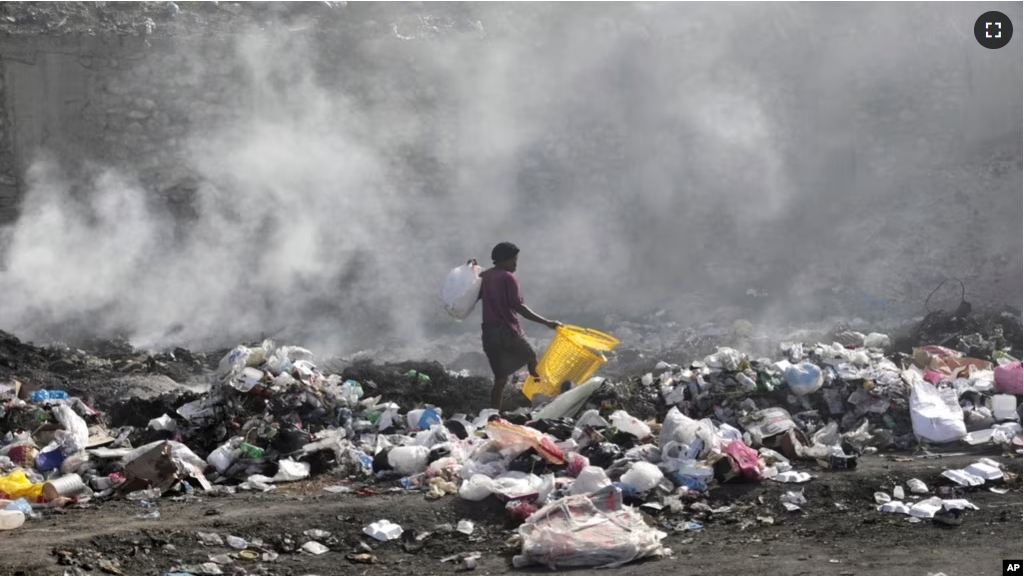 FILE - A woman walks through a landfill looking for salvageable items, in Port-au-Prince, Haiti, Saturday, July 1, 2023. (AP Photo/Odelyn Joseph)