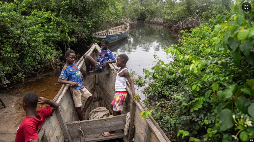 Children sit inside a fishing boat outside a mangrove in Kimpozia village, one of the areas auctioned for oil drilling, in Moanda, Democratic Republic of the Congo, Monday, Dec. 25, 2023. (AP Photo/Mosa'ab Elshamy)