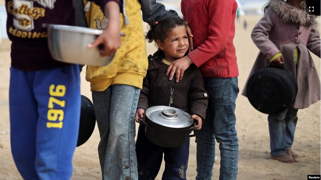 Displaced Palestinian children wait to receive free food at a tent camp as the conflict between Israel and Hamas continues, in Rafah in the southern Gaza Strip, Feb. 27, 2024. (REUTERS/Ibraheem Abu Mustafa )