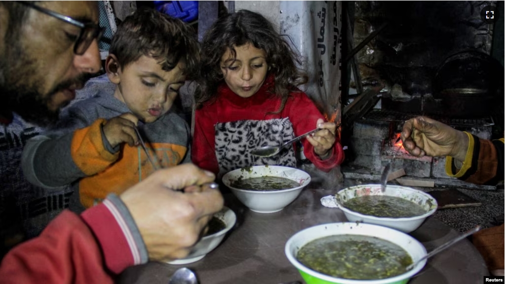 Displaced Palestinian man Wael Al-Attar eats Khobiza, a wild leafy vegetable, with his family as they break their fast during the holy month of Ramadan, at a school where they shelter, in Jabalia in the northern Gaza Strip, March 22, 2024. (REUTERS/Mahmoud Issa)