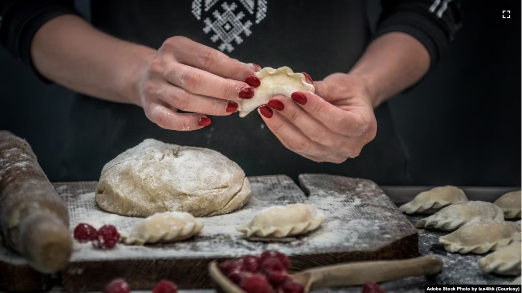FILE - Woman makes a delicious Ukrainian national food, varenyky with raspberry. (Adobe Stock Photo by tan4ikk)