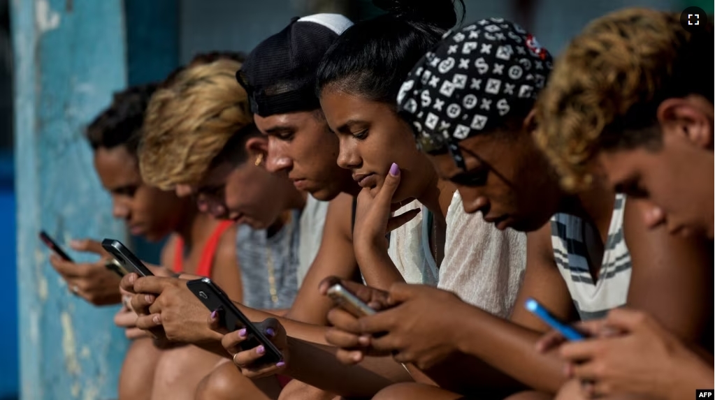 FILE - Young people use a hotspot to connect to the internet, in Havana, Cuba, June 06, 2019.