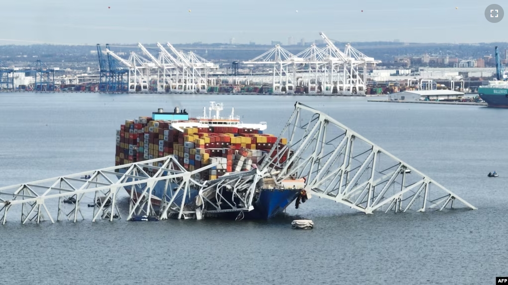 In this aerial image, the steel frame of the Francis Scott Key Bridge sits on top of a container ship after the bridge collapsed, in Baltimore, Maryland, on March 26, 2024. (Photo by Jim WATSON / AFP)