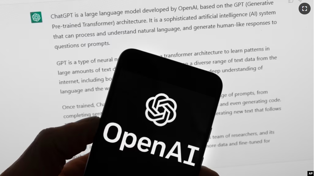 The OpenAI logo is seen on a mobile phone in front of a computer screen which displays output from ChatGPT, March 21, 2023, in Boston.(AP Photo/Michael Dwyer, File)