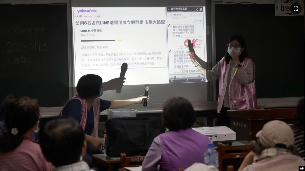 Volunteers of Fake News Cleaner guide students through the LINE app to identify fake news during a class in Kaohsiung City, southern Taiwan, Thursday, March 16, 2023. (AP Photo/Chiang Ying-ying)