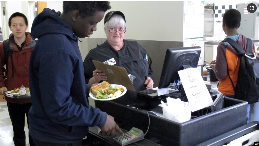 FILE - In this Friday, April 5, 2019 photo, a student buys lunch in the cafeteria at Burlington High School in Burlington, Vermont. (AP Photo/Wilson Ring)