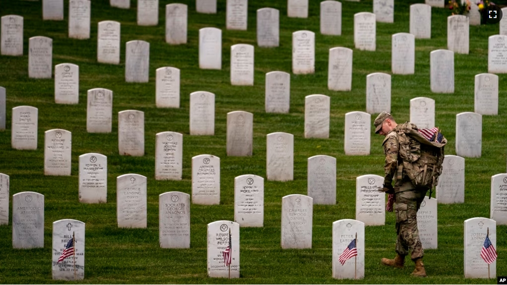 FILE - A member of The Old Guard, places flags in front of each headstone for "Flags-In" at Arlington National Cemetery in Arlington, May 25, 2023, to honor the Nation's fallen military heroes ahead of Memorial Day. (AP Photo/Andrew Harnik, file)