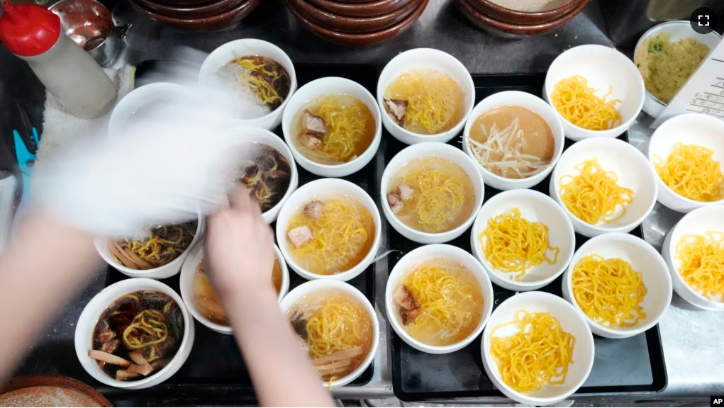 A staff member prepares small bowls of noodles for participants of Tokyo Ramen Tours at Shinbusakiya, a ramen shop that offers "Hokkaido classics," at Shibuya district on April 2, 2024, in Tokyo. (AP Photo/Eugene Hoshiko)