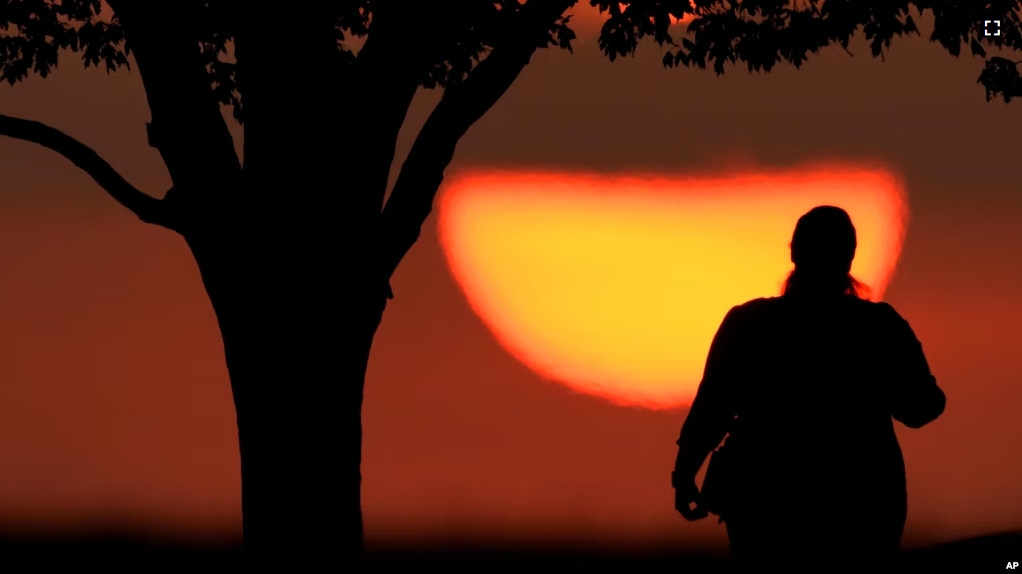 FILE - A woman watches the sun sets on a hot day, Aug. 20, 2023, in Kansas City, Mo. A new study on May 14, 2024, finds that the summer of 2023 was the hottest in the Northern Hemisphere in more than 2,000 years. (AP Photo/Charlie Riedel, File)