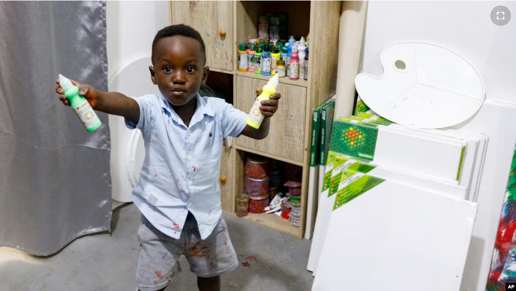 Ace-Liam Nana Sam Ankrah, who will turn two in July, shows off his paint tubes at his mother's art gallery in Accra, Ghana, Monday, May 27, 2024. (AP Photo/Misper Apawu)