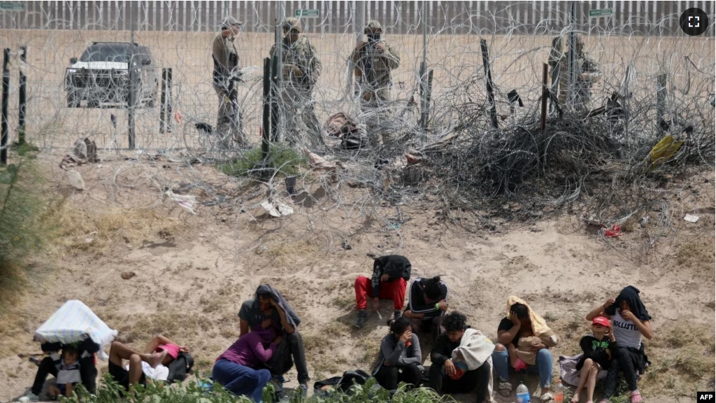 Migrants seeking asylum in the United States are watched by the Texas National Guard while they remain on the bank of the Rio Grande after having crossed from Ciudad Juarez, Chihuahua State, Mexico, on June 4, 2024. (Photo by HERIKA MARTINEZ / AFP)