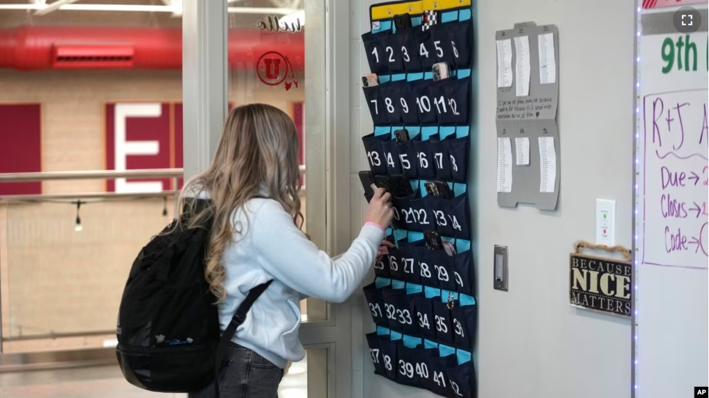 FILE - A student places her cellphone into a phone holder as she enters class at Delta High School, Friday, Feb. 23, 2024, in Delta, Utah. (AP Photo/Rick Bowmer)