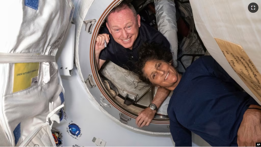 In this photo provided by NASA, Boeing Crew Flight Test astronauts Butch Wilmore, left, and Suni Williams pose inside the International Space Station's Harmony module and Boeing's Starliner spacecraft on June 13, 2024. (NASA via AP)