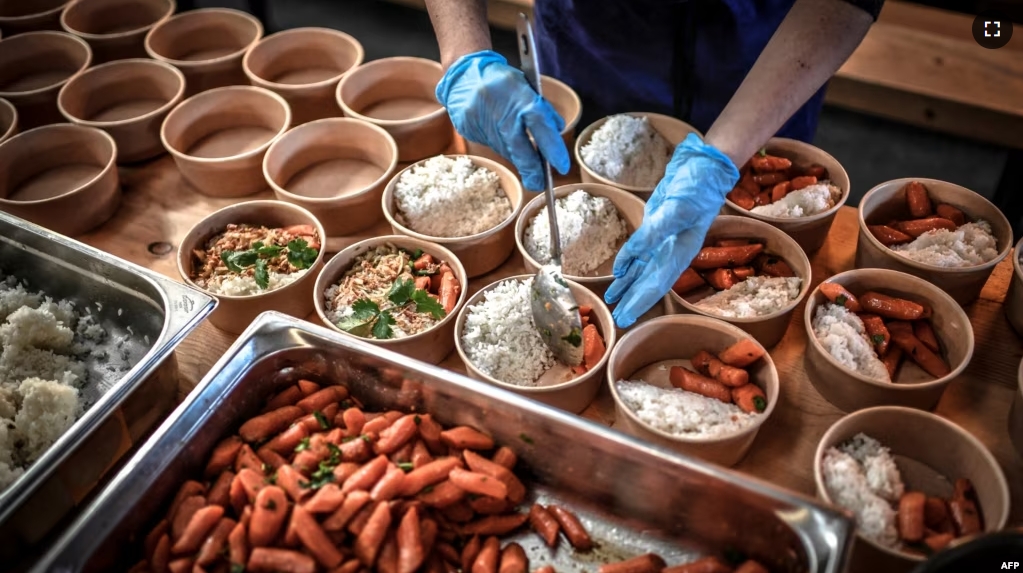 FILE - A volunteer for "Refugee Food" prepares food for students in need on March 9, 2021, in Paris. (Photo by STEPHANE DE SAKUTIN / AFP)