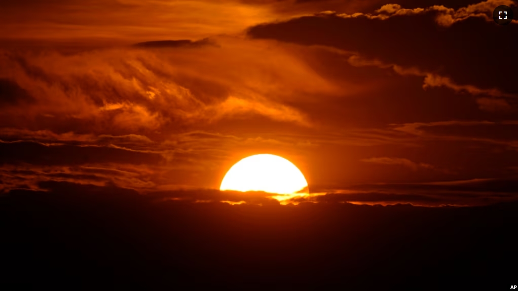 FILE - The setting sun illuminates the clouds over the Rocky Mountains after a third straight day of record-breaking heat Sunday, July 14, 2024, in Denver. (AP Photo/David Zalubowski)