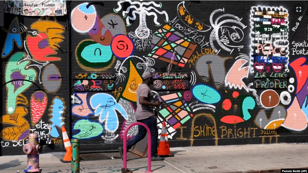 A man walks past a mural in the Harlem neighborhood of New York, Thursday, Aug. 15, 2024. (AP Photo/Pamela Smith)