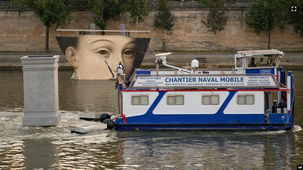 A ship sails past reproductions of artworks decorating the banks of the River Seineat the 2024 Summer Olympics, Tuesday, July 30, 2024, in Paris, France. (AP Photo/Vadim Ghirda)