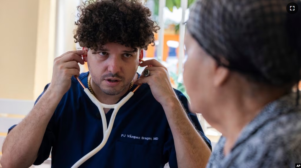 Dr. Pedro Juan Vázquez, better known by his stage name PJ Sin Suela, attends to a patient in Loiza, Puerto Rico, Saturday, May 25, 2024. (AP Photo/Alejandro Granadillo)