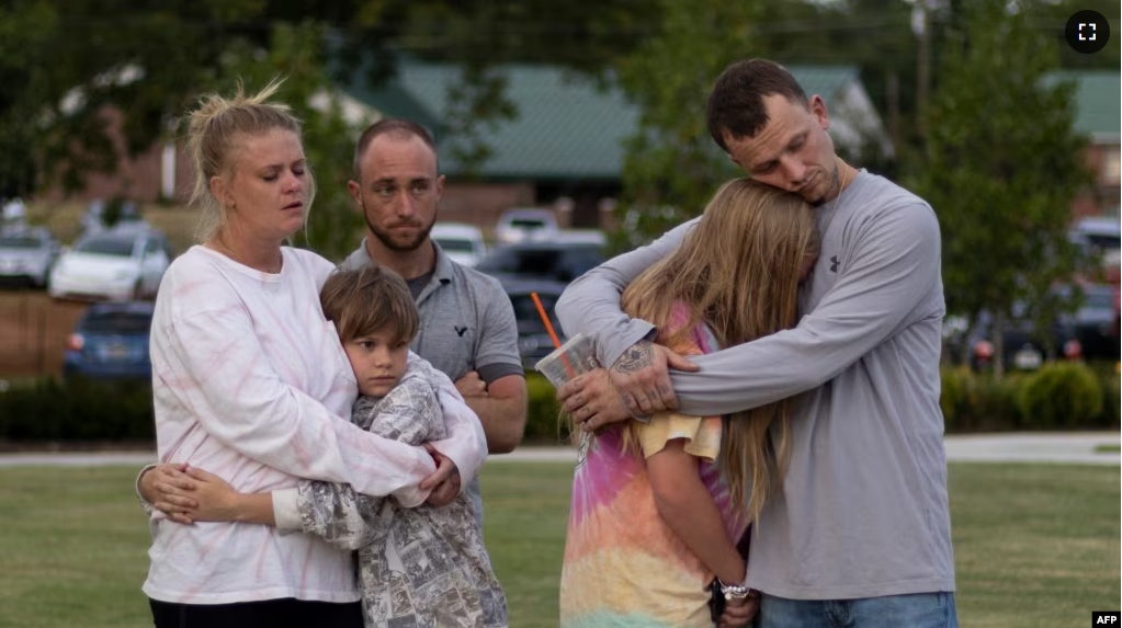 FILE - A family embraces during a vigil for the victims of the Apalachee High School shooting at Jug Tavern Park in Winder, Georgia, on September 4, 2024, after a shooting took place. (Photo by CHRISTIAN MONTERROSA / AFP)