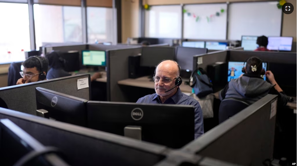 FILE - Customer Experience Representatives Stanley Solis, center, and other representatives take calls at an Alorica center, Monday, Aug. 19, 2024, in San Antonio. (AP Photo/Eric Gay)