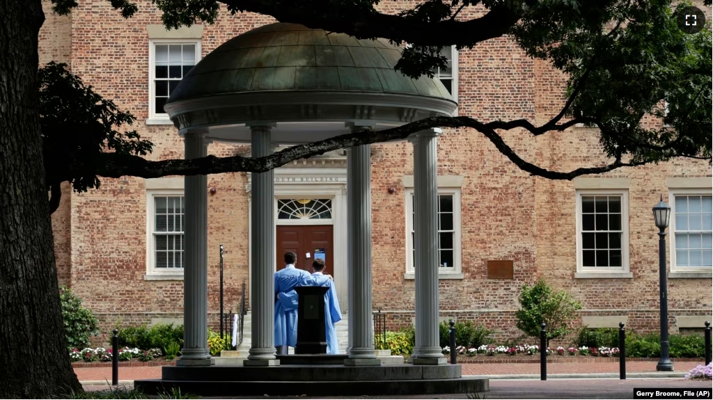 FILE - Graduates of the University of North Carolina take pictures at the Old Well on campus in Chapel Hill, N.C., June 30, 2020. (AP Photo/Gerry Broome, File)