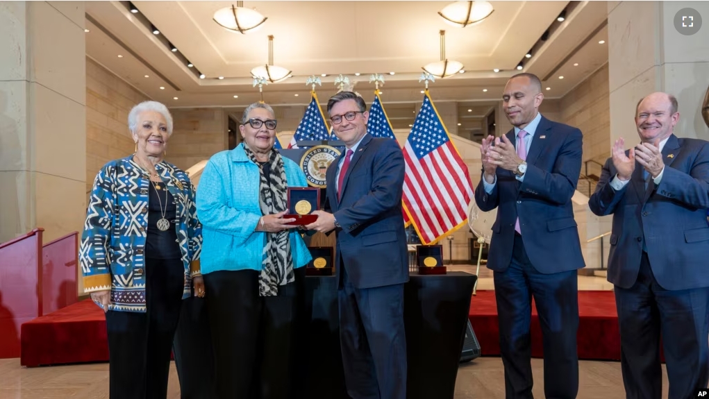 House Speaker Mike Johnson, center, presents a Congressional Gold Medal posthumously to Joylette Hylick, left, and Katherine Moore, daughters of Katherine Johnson at the Capitol in Washington, Sept. 18, 2024.