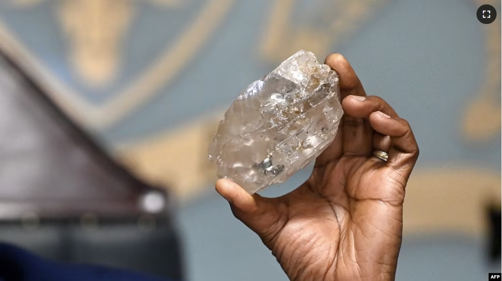 Botswana's President Mokgweetsi Masisi holds a large diamond discovered in Botswana at his office in Gaborone on August 22, 2024. (Photo by Monirul BHUIYAN / AFP)