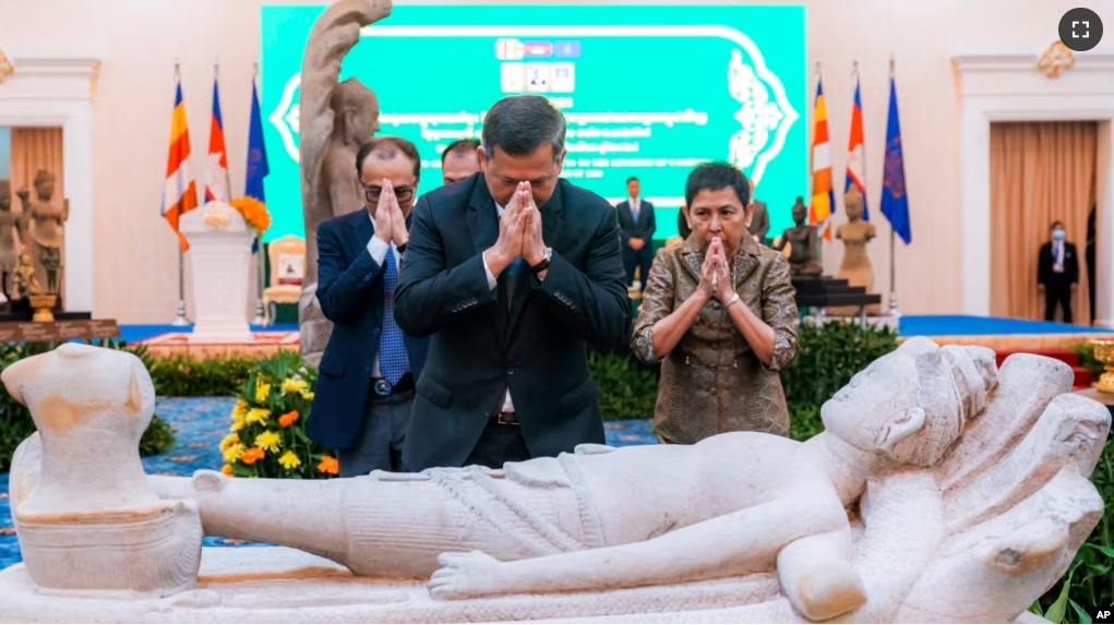 In this photo released by Agence Kampuchea Press (AKP), Cambodian Prime Minister Hun Manet prays with others during a ceremony for the return of artifacts in Peace Palace in Phnom Penh, Cambodia, Thursday, Aug. 22, 2024. (AKP via AP)