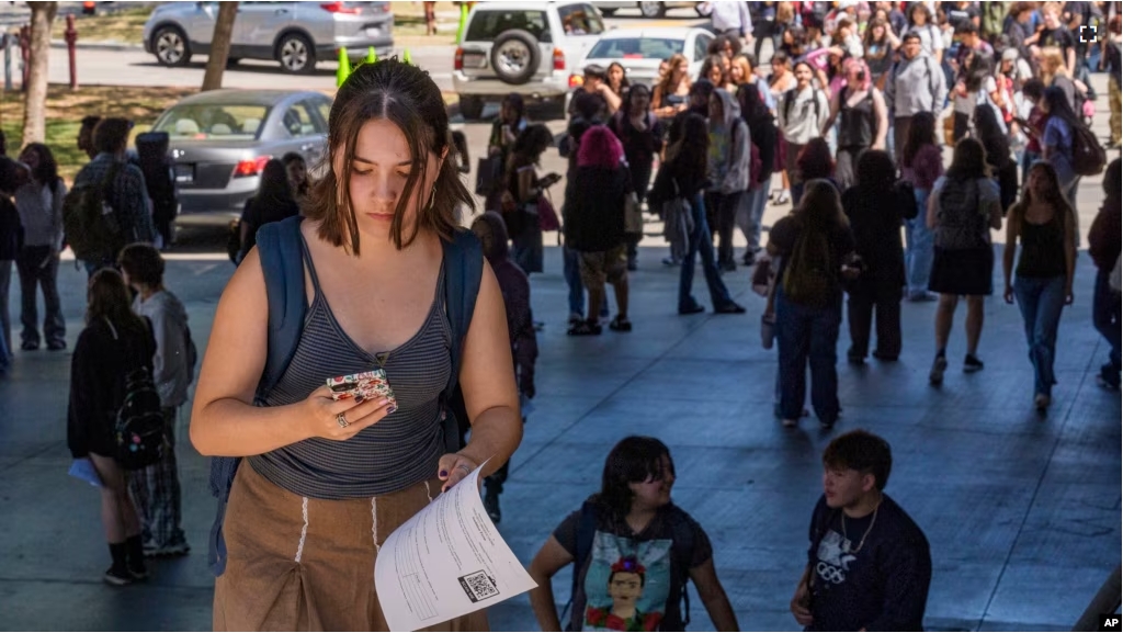 FILE - Student Keiran George uses her cellphone as she steps outside the Ramon C. Cortines School of Visual and Performing Arts High School in downtown Los Angeles on Tuesday, Aug. 13, 2024. (AP Photo/Damian Dovarganes)