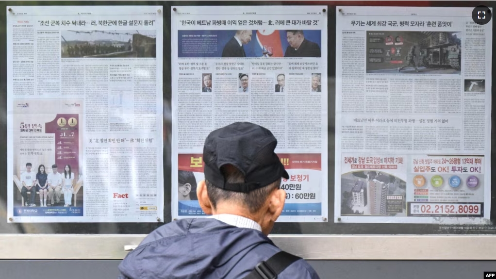 A man walks past a newspaper displayed on a street for the public in Seoul on October 21, 2024, with coverage on North Korea's decision to deploy thousands of soldiers to Ukraine. (Photo by Anthony WALLACE / AFP)