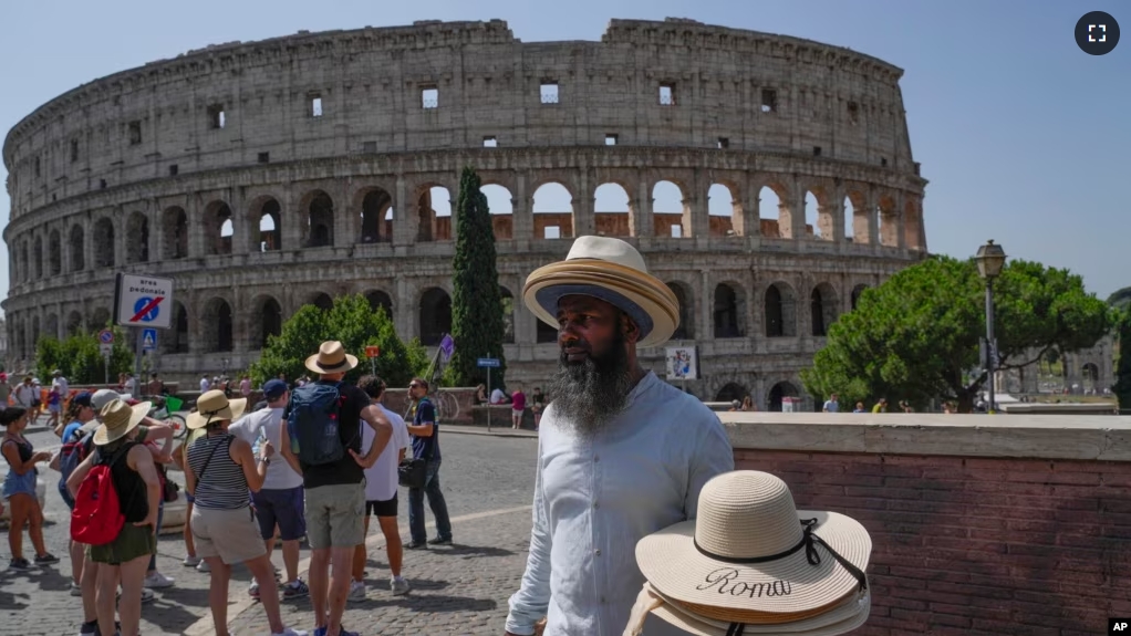 FILE - A street vendor sells hats in front of the Colosseum in Rome, Monday, July 17, 2023. (AP Photo/Gregorio Borgia)