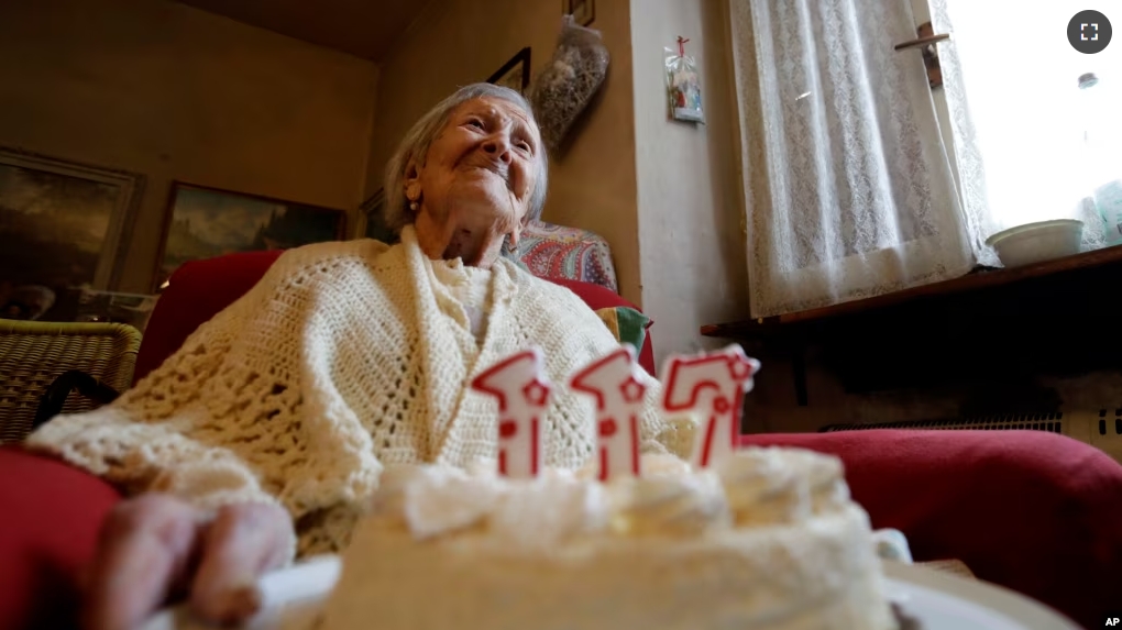 FILE - Emma Morano holds a cake with candles marking 117 years on the day of her birthday, Nov. 29, 2016, in Verbania, Italy. (AP Photo/Antonio Calanni)