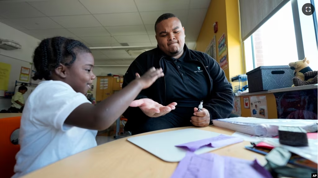 Leading Men fellow Davontez Johnson, right, high-fives preschooler Kodi during a name writing exercise, Thursday, Oct. 3, 2024, at Dorothy I. Height Elementary School in Baltimore. (AP Photo/Stephanie Scarbrough)