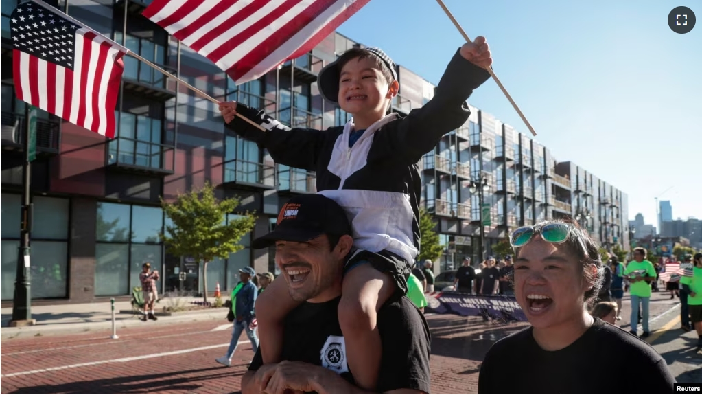 FILE - Sheet Metal Union member Dan Hines carries Jackson Kin on his shoulders as he and Erica Kin march in the annual Labor Day Parade in Detroit, Michigan, U.S., September 2, 2024. (REUTERS/Rebecca Cook)