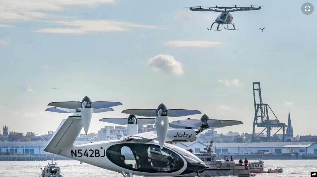 This file images shows an electric vertical takeoff and landing (eVTOL) aircraft, flying above the Joby eVTOL aircraft, during a demonstration of eVTOLs Nov. 13, 2023, in New York. (AP Photo/Bebeto Matthews, File)