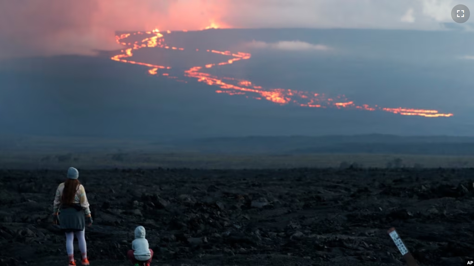 In this file photo, onlookers watch the lava flow down the mountain from the Mauna Loa eruption, Tuesday, Nov. 29, 2022, near Hilo, Hawaii. (AP Photo/Marco Garcia, File)