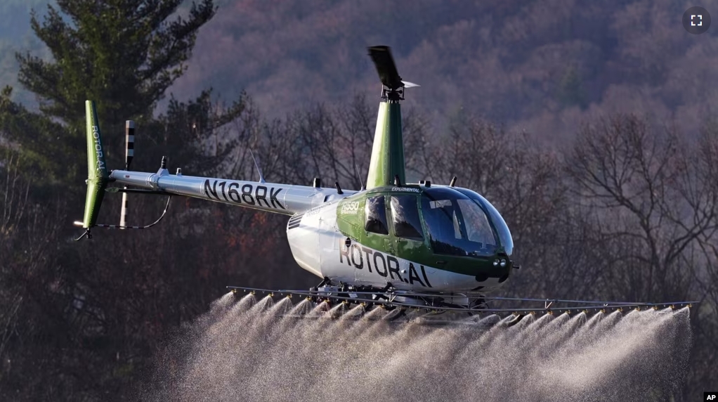 A Rotor Technologies unmanned semi-autonomous helicopter sprays a payload of water during a test flight over Intervale Airport, Monday, Nov. 11, 2024, in Henniker, N.H. (AP Photo/Charles Krupa)