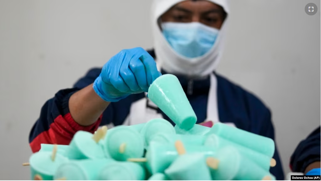 A worker packages popsicles at an artisanal factory in Salcedo, Ecuador, Thursday, Nov. 28, 2024, amid a wave of power outages, triggered by a prolonged dry spell. (AP Photo/Dolores Ochoa)