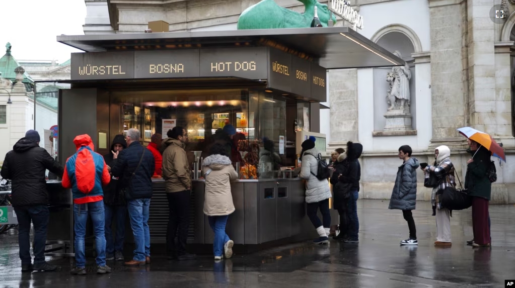 Customers line up at a traditional sausage stand (Wuerstelstand), which are named as intangible cultural heritage by the Austrian UNESCO Commission, in Vienna, Austria, Thursday, Nov. 28, 2024. (AP Photo/Heinz-Peter Bader)