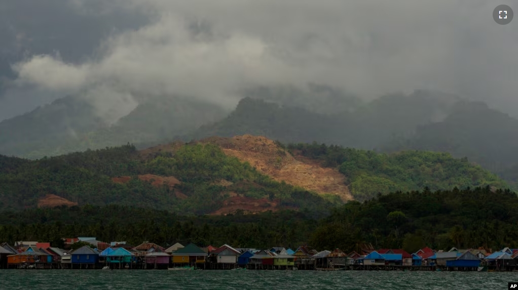 A nickel mine is visible on top of a hill above a village on Kabaena Island, Indonesia, Thursday, Nov. 14, 2024. (AP Photo/Yusuf Wahil)