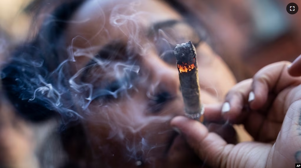 FILE - A person smokes cannabis outside the Smacked "pop up" cannabis dispensary location, Tuesday, Jan. 24, 2023, in New York. (AP Photo/John Minchillo)